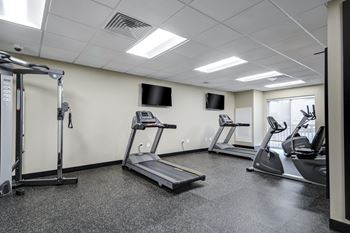 two treadmills and other exercise equipment in a gym with a tv at Residences at the Street, Washington, Pennsylvania